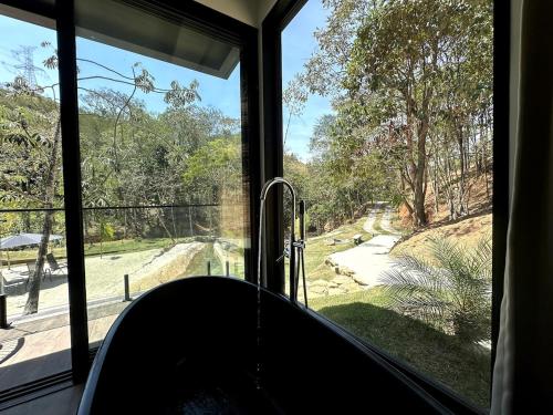 a room with a window with a view of a yard at Chalé com banheira, piscina e cachoeira privativa in Taubaté