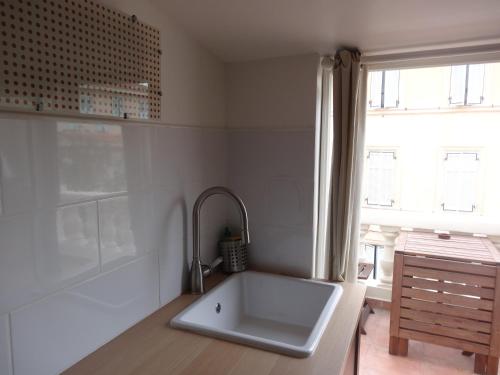 une cuisine blanche avec un évier et une fenêtre dans l'établissement Studio Panier 1930, à Marseille