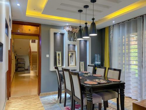 a dining room with a black table and chairs at Maison Princeton in Kampala