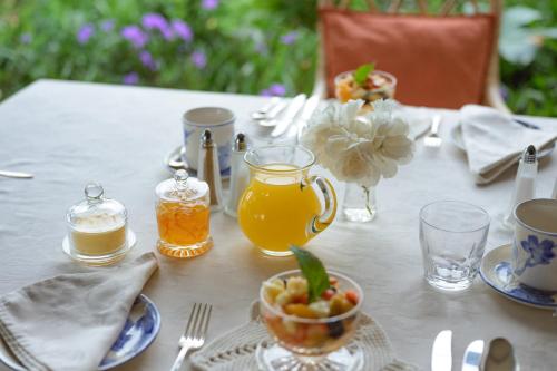 a table with a white table cloth with juice and a bowl of fruit at Lupus Den Country House B&B in Sunland