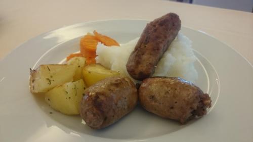 a plate of food with sausage potatoes and carrots at Hotel Bristol in Lignano Sabbiadoro
