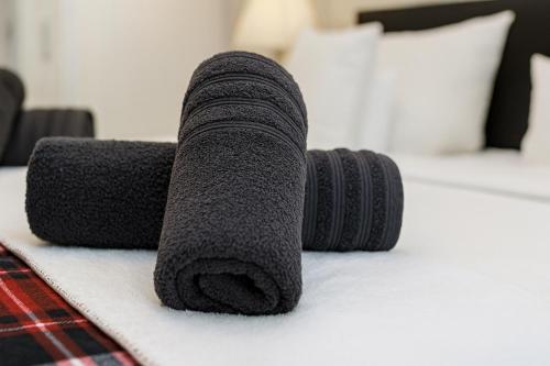 een stapel zwarte handdoeken op een bed bij Gelbe Koffer - Design-Apartment in Schiffweiler - Self-Check-in - 2 Parkplätze - WLAN - Balkon mit Gartenzugang - private Terrasse - ruhig gelegen - Nähe See & Wald - bis 4 Pers in Schiffweiler