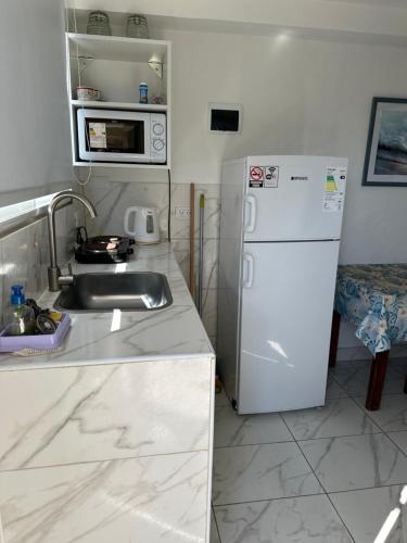 een keuken met een wastafel en een witte koelkast bij Bilbao 44 in Santa Clara del Mar