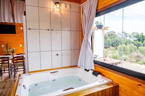 Una bañera en una habitación con una ventana grande. en Chico Cabanas, en Lajeado Grande