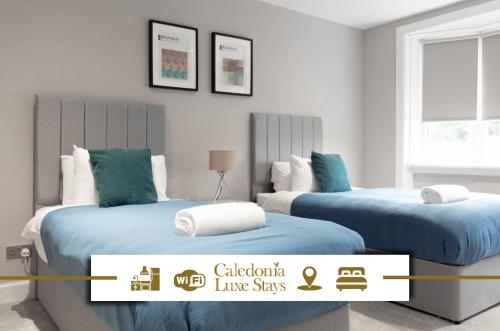 two beds with blue sheets in a room at Castlemilk Apartment in Glasgow