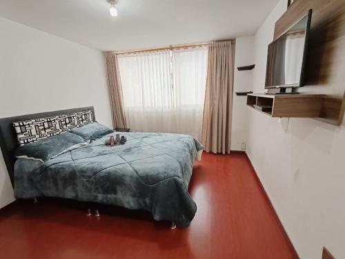 a bedroom with a bed and a flat screen tv at Apartaestudio céntrico y acogedor con cocina y WiFi Tunja in Tunja