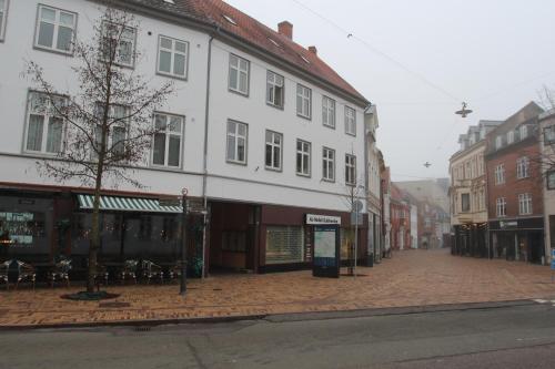 a city street with a white building and tables and chairs at The Cozy Cave Odense Center in Odense
