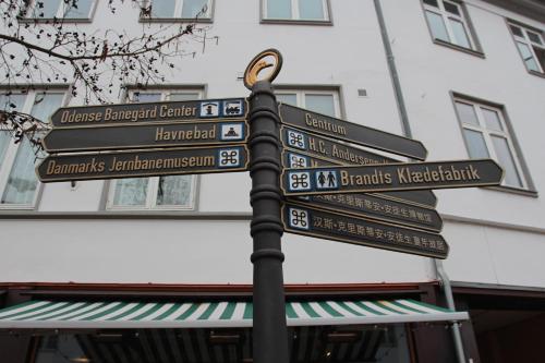 een straatbord met een routebeschrijving naar verschillende steden bij The Cozy Cave Odense Center in Odense