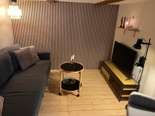 een woonkamer met een bank en een tafel met een kaars bij The Cozy Cave Odense Center in Odense