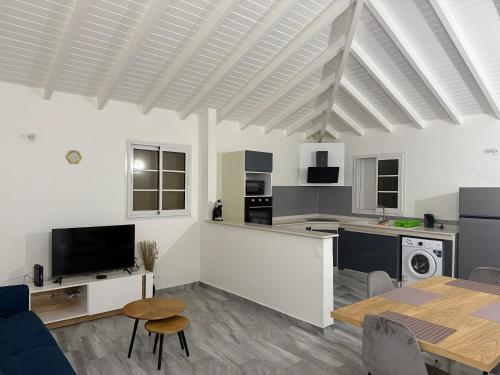 a living room with a table and a kitchen at Gîtes Royal passion in Saint-François