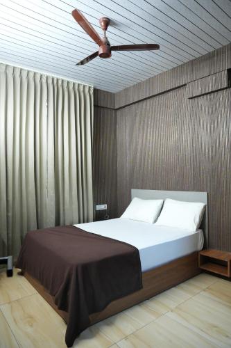 Grand sapphire 100 meters from Sub urban Bus stand Mysore في ميسور: غرفة نوم بها سرير ومروحة سقف