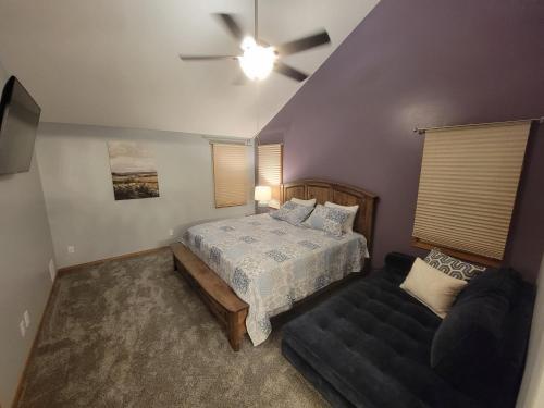 Home away from home في Urbandale: غرفة نوم بسرير واريكة ومروحة سقف