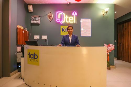 FabHotel Maxx Inn في نيودلهي: امرأة تقف خلف مكتب الاستقبال