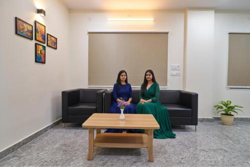 two women sitting on a couch in a room at Via RS Living - Nr TCS Deccan Park, Hitech City in Hyderabad