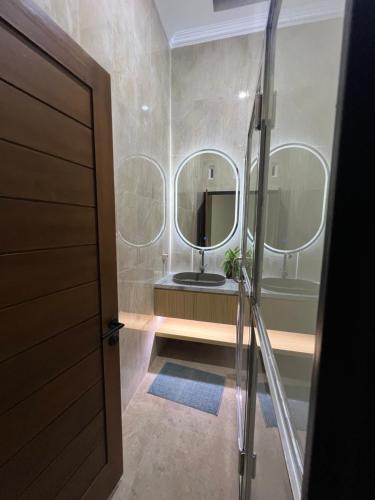a bathroom with a sink and two mirrors at Tentrem Madani in Yogyakarta