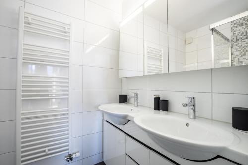 Un baño blanco con dos lavabos y un espejo. en A&Y Alpenchique Apartment Davos, en Davos