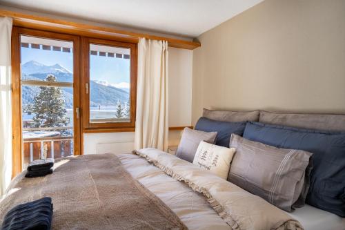 Un dormitorio con una cama grande con una ventana grande. en A&Y Alpenchique Apartment Davos, en Davos