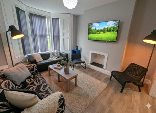 a living room with a couch and a tv on the wall at Summerhill Sunderland Business Stay 6 Private Ensuite Rooms in Sunderland