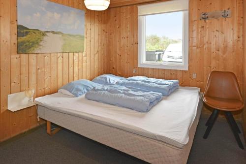 a bed in a room with a chair and a window at 525-Vestervig-Spovevej-5 in Vestervig