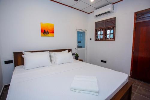 een slaapkamer met een groot wit bed met witte kussens bij jenul villa in Ahangama