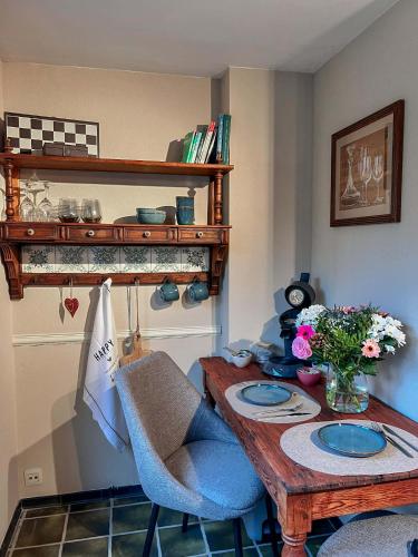 a room with a wooden table with a chair and flowers at Le Relais d'Hubert in Saint-Hubert