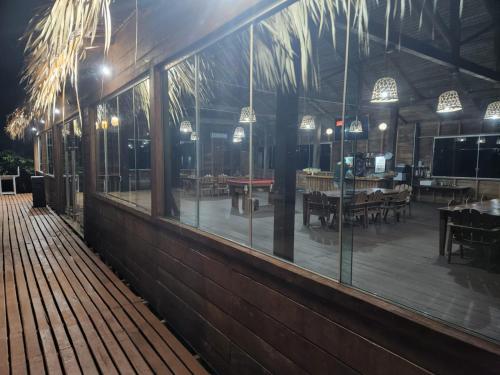 马瑙斯Amazon Tucuna Resort的一家拥有落地玻璃窗和带餐桌的露台的餐厅