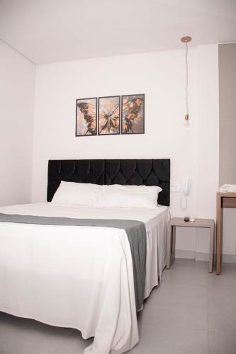 a bedroom with a white bed with a black headboard at Oscar flats in Montes Claros