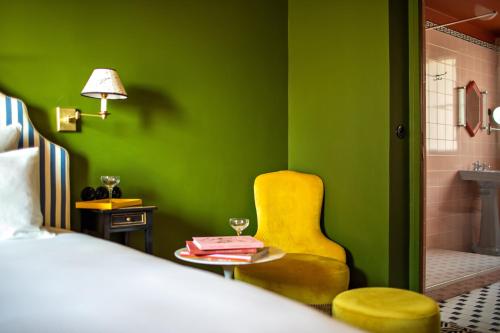 Hôtel Les Deux Gares & Spa في باريس: غرفة نوم خضراء بسرير وكرسي اصفر
