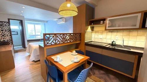 a room with a table and a kitchen and a bed at Pousada Gamboa estações in Garopaba