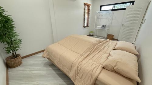 a bedroom with a bed with a blanket on it at No 5 Home in Ratchaburi