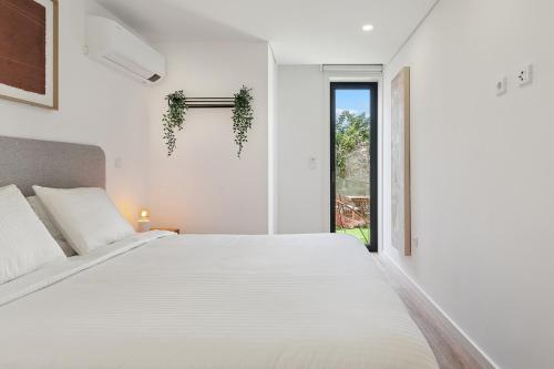 Un dormitorio blanco con una cama grande y una ventana. en Private Garden Oasis, A Charming Flat in Bonfim, en Bicas