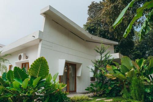 Una pequeña casa blanca con árboles y plantas. en Nong Lam Ecolodge, en Linh Xuân Thôn