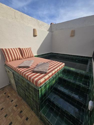 a bed on a balcony with green tiles at Riad Alaya, Rooftop Pool & Koutoubia View in Marrakesh