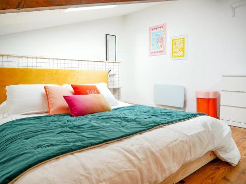 Gîte du Puy Drome Provençale Puygiron في Puygiron: غرفة نوم مع سرير كبير مع وسائد ملونة