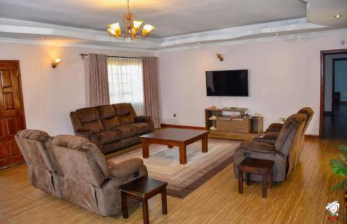 a living room with couches and a table and a tv at Tranquil villa in Kitale