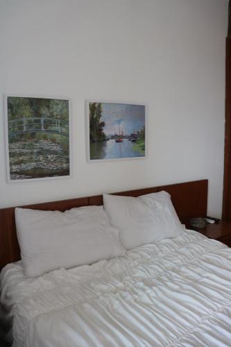a white bed with two pictures on the wall at Ocean Flat vista mar in Vila Velha