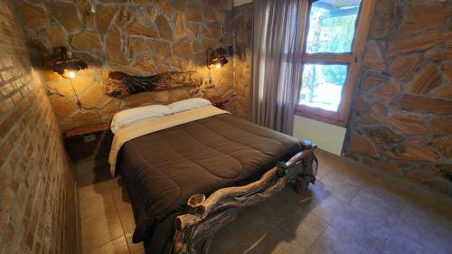 a bedroom with a bed in a stone wall at Cabañas Altos de la Bodega in San Rafael