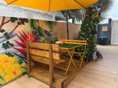a patio with a table and a bench and an umbrella at Maison charmante à Fort-de-France avec équipements modernes in Fort-de-France