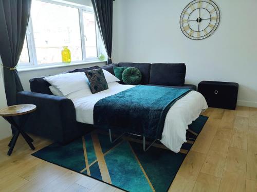 a bedroom with a bed with a couch and a clock at Fresh Spring Getaway-Christchurch Town Centre in Christchurch