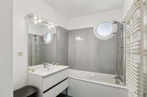 Un baño blanco con bañera y lavabo. en Superbe 90M2, chic & cosy avec Parking privé et Terrasse - 10pers, en Villeurbanne