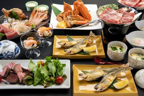 a table topped with plates of food with fish at Sunhills Sarai in Shintotsukawa
