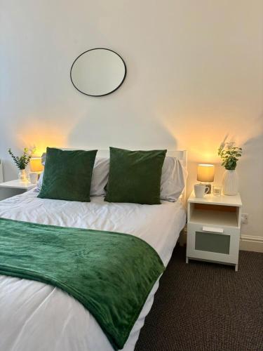 ein Schlafzimmer mit einem Bett, auf dem eine grüne Decke liegt in der Unterkunft Modern & Spacious 2-bed flat - Central Cardiff - Fast Wifi - Long & Short Stay in Cardiff