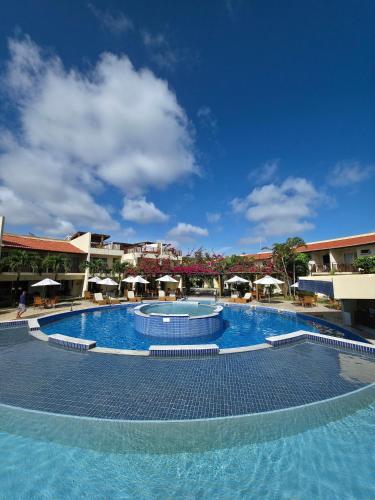 uma grande piscina num resort com guarda-sóis em Solar Águas Pipa Stays em Pipa