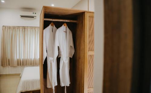 a wooden closet with white shirts hanging in it at Nong Lam Ecolodge in Linh Xuân Thôn