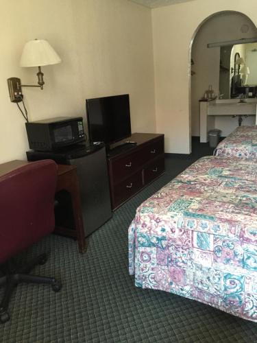 a hotel room with a bed and a desk and a television at Perimeter Inn - Athens in Athens