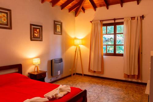 La Cuyanita - Complejo de cabañas في ميرلو: غرفة نوم بسرير احمر ونافذة