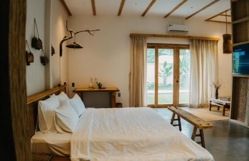 a bedroom with a white bed and a large window at Nong Lam Ecolodge in Linh Xuân Thôn