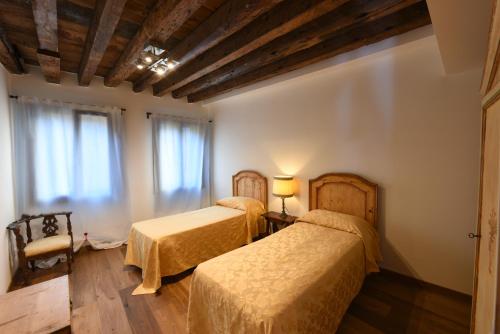 1 dormitorio con 2 camas y ventana en Mercerie e Capitello Apartments, en Venecia