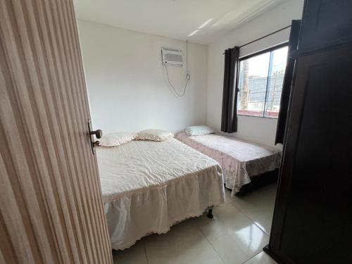 Un dormitorio con dos camas y una ventana. en Apto Ninho Sereno em ilheus, en Ilhéus