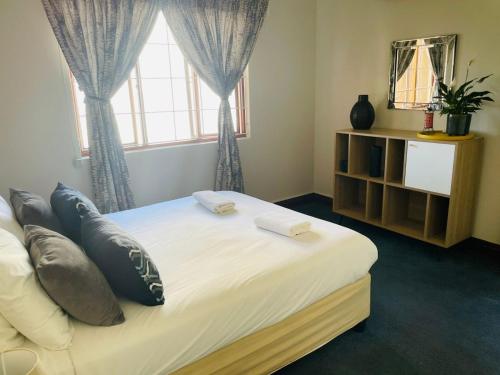 a bedroom with a bed with pillows and a window at 5 OYSTER COTTAGE in Durban